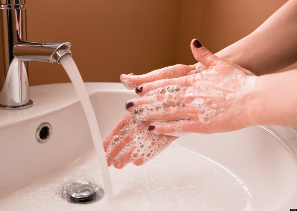 HW - Indelible Learning Picture showing bubbly hands performing hand washing under a running faucet.